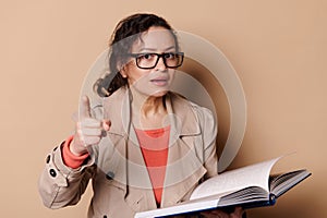 Strict female teacher with glasses, points her index finger at camera, warning you about the importance of reading books