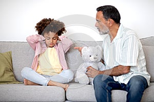 Strict Grandpa Scolding His Grandson, While Boy Covering Ears Indoors