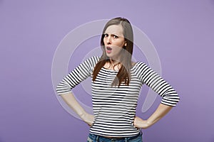 Strict irritated young brunette woman in casual striped clothes posing isolated on violet purple background. People