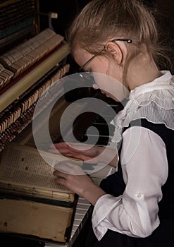 Strict little girl in a big glasses playing the piano, child imitates teacher