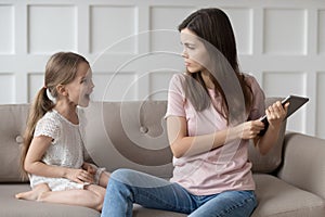 Strict mother scolding little daughter for long computer tablet use