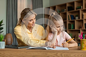 Strict mother studying with little schoolgirl daughter, scolding lecture for bad marks, girl unmotivated to do homework