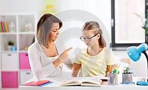 Strict mother talking to daughter doing homework