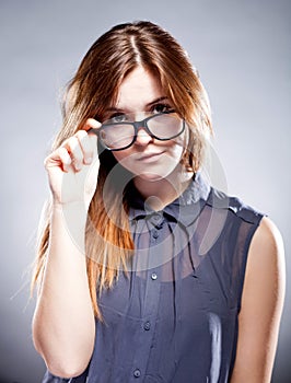 Strict serious young woman holding nerd glasses