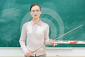 Strict teacher standing in front of blackboard in class