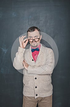 Strict teacher vintage style in eyeglasses looking at you on blackboard