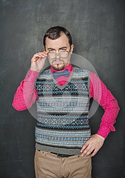 Strict teacher vintage style in eyeglasses looking at you on blackboard