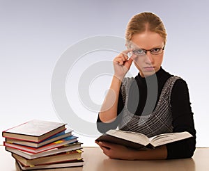 Strict woman with a book sitting at table photo