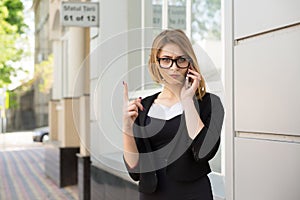 Strict woman with smartphone showing no, don`t, attention with finger hand