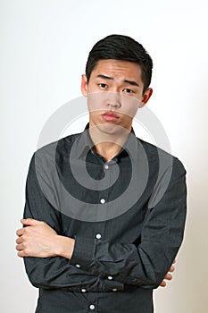 Strict young Asian man with crossed hands looking at camera