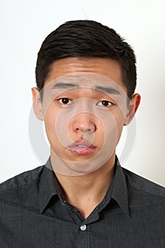 Strict young Asian man looking at camera