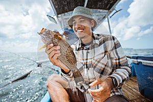 strike grouper held by an Asian angler on fishing boat