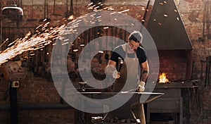 Striking cold iron is a waste of time and effort. a metal worker hitting a hot metal rod with a hammer in a welding