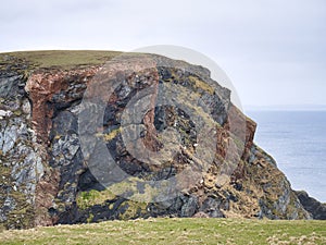 Striking mixes of different grey and red rock types in the coastal cliffs on the Ness of Hillswick in Northmavine, Shetland