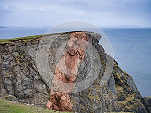 Striking mixes of different grey and red rock types in the coastal cliffs on the Ness of Hillswick in Shetland