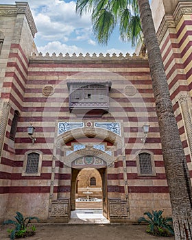 Striking red and white striped arched entrance leads into a Mamluk era style building