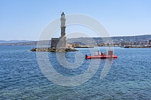 The striking semisubmarine sails past the old lighthouse into the Old harbor of Chania, Crete, Greece