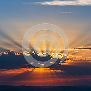 A striking sunset features rays of light streaming through dark clouds, creating a