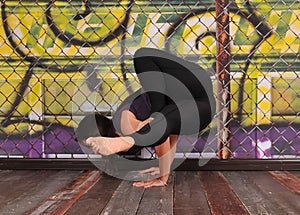 Striking yoga pose by beautiful young lady on backdrop