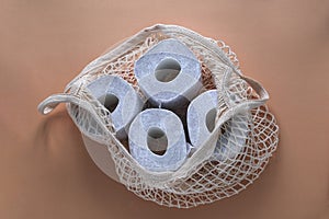 string bag full of toilet paper rolls, layout on a beige background