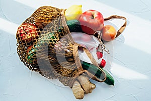 String bag with various fresh vegetables on white background