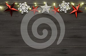 A string of golden star christmas lights, and christmas baubles, on a destressed wooden background, with room for copy space