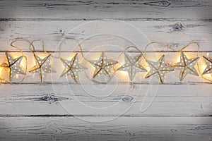 A string of golden star christmas lights, on a destressed woodern background