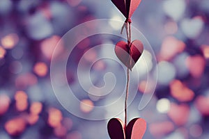 a string of hearts hanging from a string with a blurry background behind it and a string of hearts hanging from the string