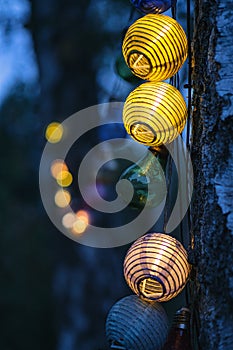 String of lights in bulb shape. Garden party or relaxing evening outdoors. Light mood with bokeh