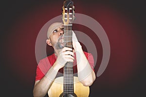 String musical instrument. Mature charismatic male guitarist. guy with beard holds guitar. bearded man in a red shirt