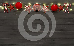 A string of red christmas decorations, lights and candy sticks, on destressed dark wood