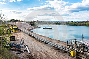 A string of transport belting in a gravel pit for transporting gravel and sand over long distances, belts go along the lake. photo