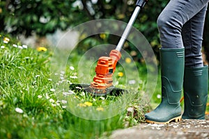 String trimmer. Woman is cutting grass in garden