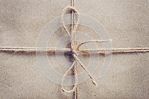 String or twine tied in a bow on brown kraft paper texture