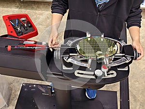 Strings a badminton racket on a racket stringing machine.