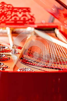 Strings close-up. Vintage red classical grand piano. Musical instrument abstract.