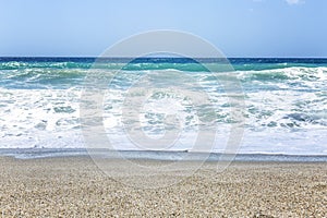 A strip of sandy beach with turquoise sea and blue sky. Beautiful landscape.