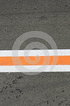 Strip of white and orange colors on a gray asphalt