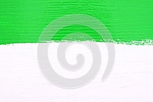 Stripe of green paint over white wooden background