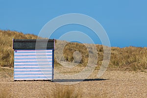 Striped beach hut on sandy beach. Secluded beach vacation.