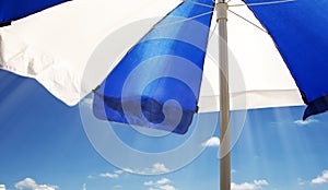 Striped beach umbrella against the sun against the blue sky