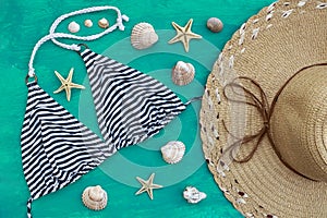 Striped bikini top and straw hat among seashells