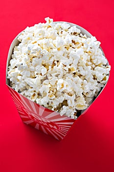 Striped box with popcorn on red background.