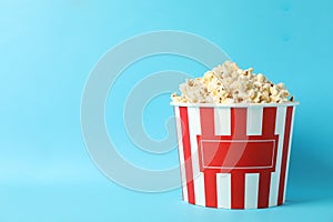 Striped bucket with popcorn on blue background