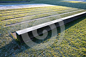 Striped composition in the park. strips of tiles and benches made of solid beams of a prismatic shape equally intersect the orname