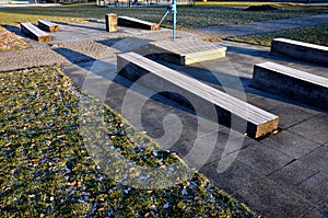 Striped composition in the park. strips of tiles and benches made of solid beams of a prismatic shape equally intersect the orname