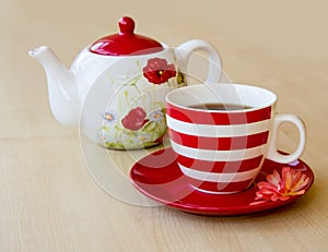 striped cup with tea on a saucer and brewer with a poppy picture