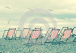 Striped deck chairs on English beach with seagulls