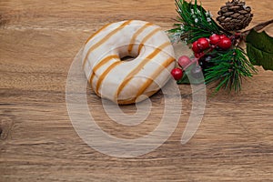 Striped Donut in glaze and festive pine branch on wooden natural background