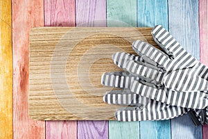 Striped gardening gloves on a wood plank, over a pastel wooden rainbow background. Useful for spring gardening concepts and